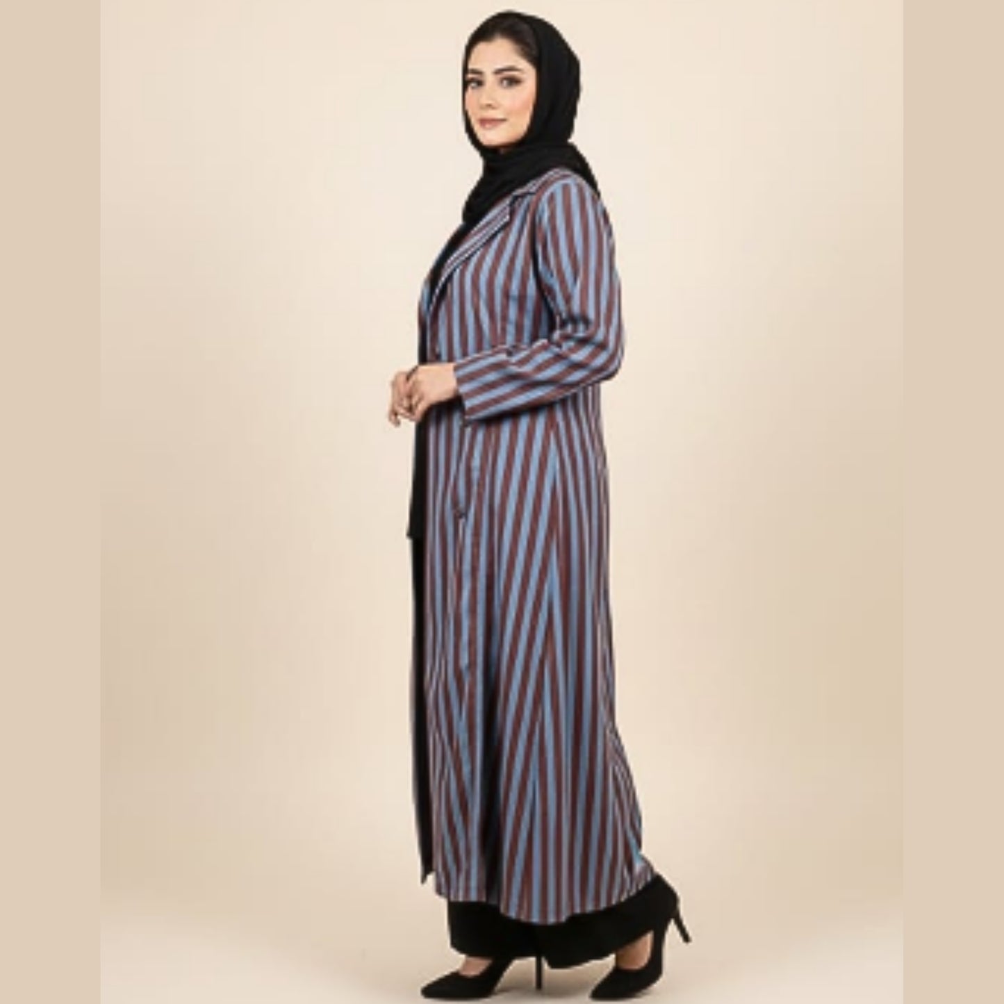 Woman wearing a striped abaya on a beige background