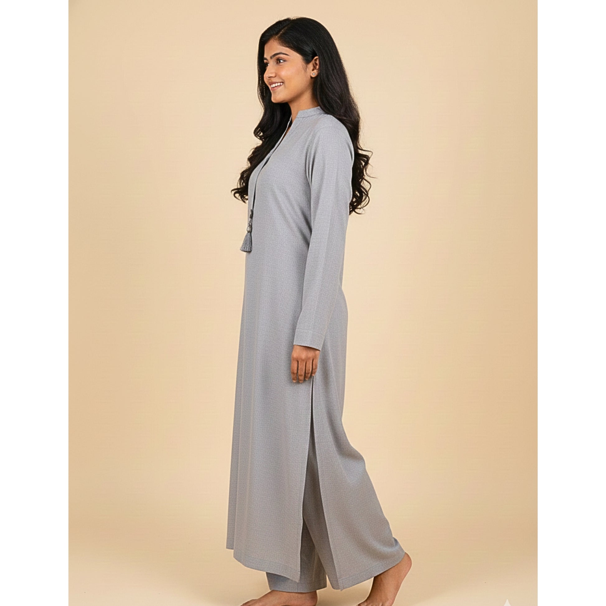 Woman wearing a long light gray dress against a beige background