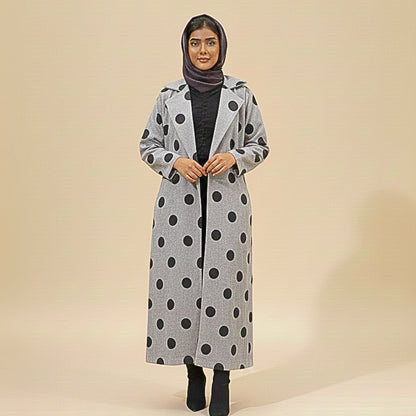 Woman wearing a long gray coat with black polka dots on a beige background