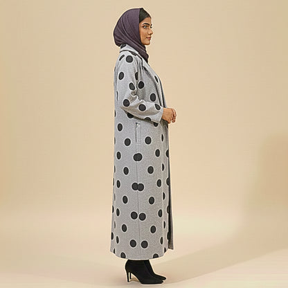 Woman wearing a long gray coat with black polka dots on a beige background