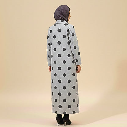 Person wearing a long polka dot coat on a beige background