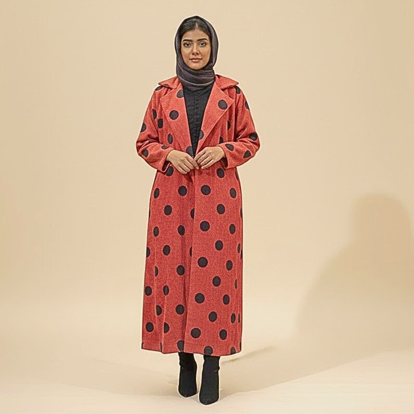 Woman wearing a red coat with black polka dots on a beige background
